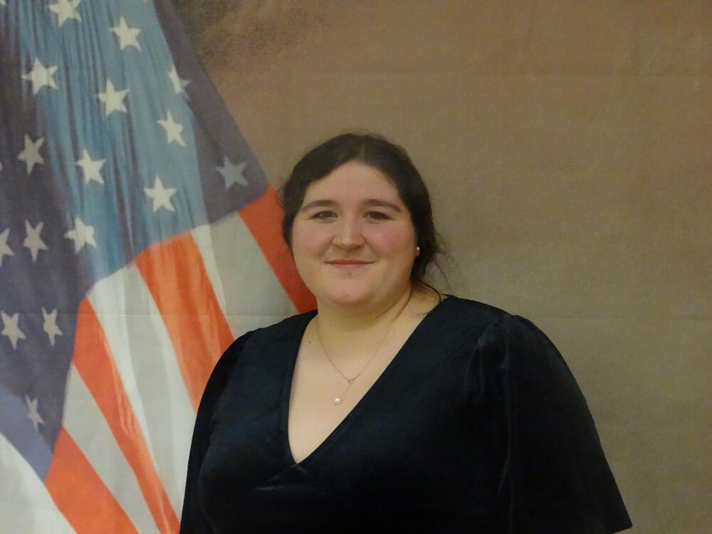 Rachael McWilliams in civilian clothing in front of the US flag